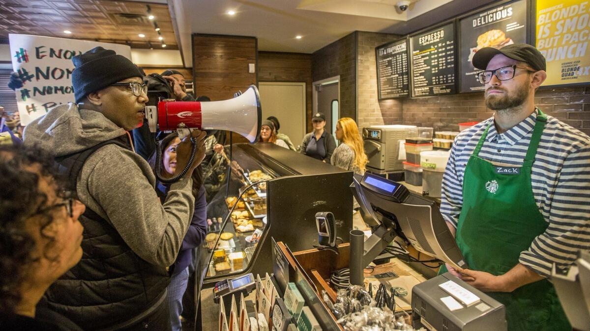Black Lives Matter activist Asa Khalif holds a bullhorn inside a Starbucks store in Philadelphia on Sunday, demanding the firing of the manager who called police on two black patrons.
