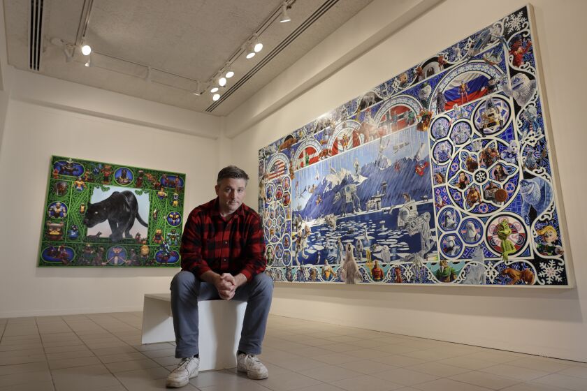 OCEANSIDE, CA - MARCH 23, 2023: Artist Robert Xavier Burden with his paintings "The Battle For The Arctic", right, and "The Panther Painting" at the Oceanside Museum of Art in Oceanside on Thursday, March 23, 2023. (Hayne Palmour IV / For The San Diego Union-Tribune)