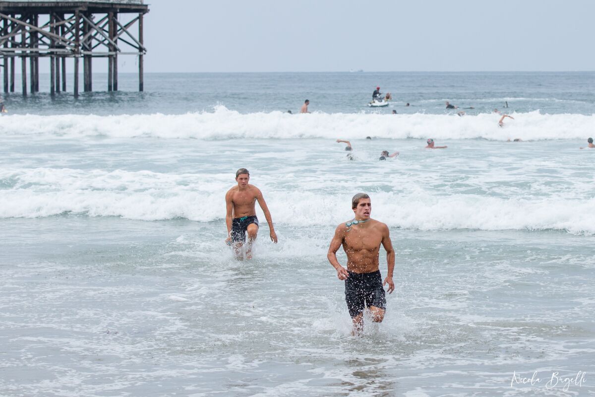 Senior Gavin Olson leads fellow La Jolla High School water polo players to the finish of a beach run-swim-run training event.