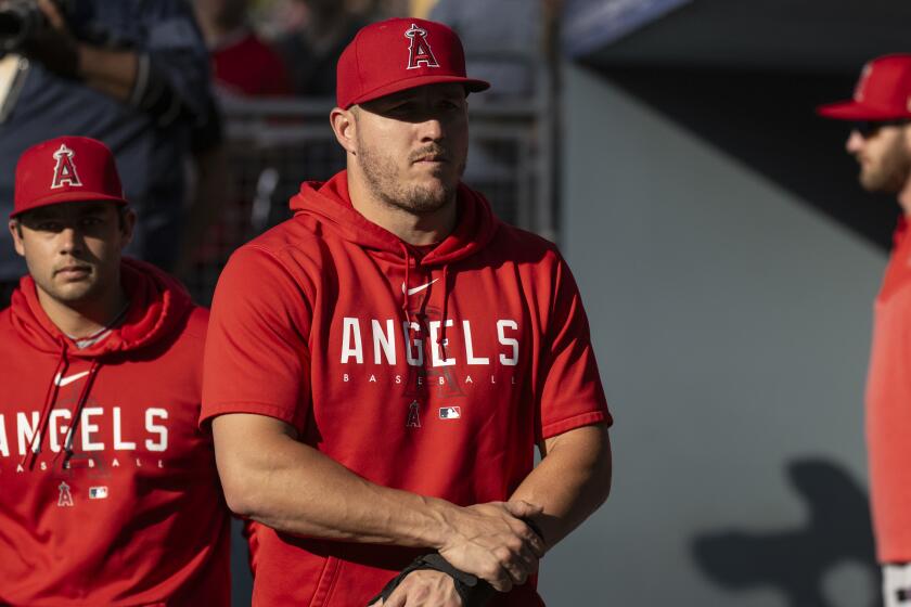 Los Angeles Angels' Mike Trout walks in the dugout before a baseball game.
