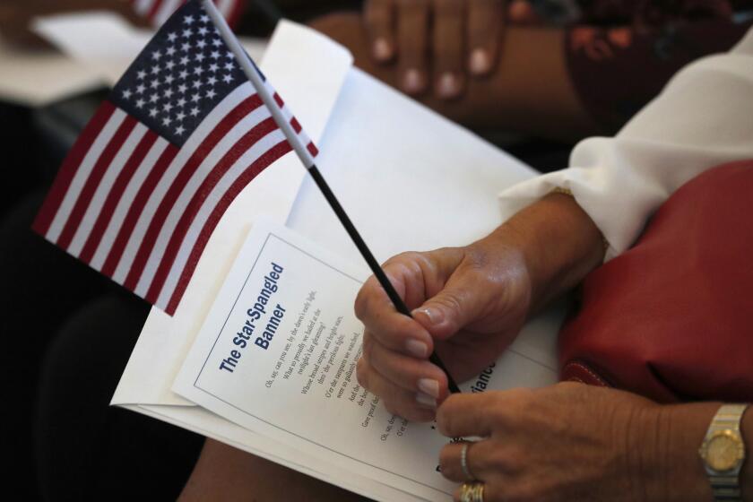 FILE - In this Aug. 16, 2019, file photo a citizen candidate holds an American flag and the words to The Star-Spangled Banner before the start of a naturalization ceremony at the U.S. Citizenship and Immigration Services Miami field office in Miami. One hundred fifty people from 40 countries took the Oath of Allegiance to become citizens during the ceremony. Foreign-born residents had higher rates of being employed than those born in the United States last year, and naturalized immigrants were more likely to have advanced degrees than the native-born, according to figures released Monday, Aug. 19, by the U.S. Census Bureau. (AP Photo/Wilfredo Lee)