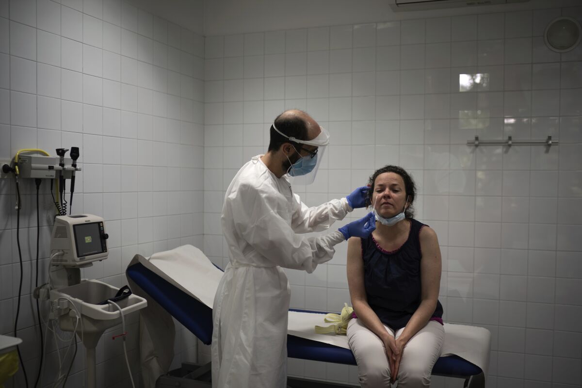 In this July 31, 2020 file photo, Emma Gaya is tested for COVID-19 at a Primary Health Care Center in Sant Sadurní d'Anoia, Catalonia region, Spain. Spaniards thought the worst of the pandemic was behind them but they are being surprised by a new wave of infections. Outbreaks among farm workers and young people desperate to resume socializing after being cooped up have spread across northern Spain. (AP Photo/Felipe Dana)