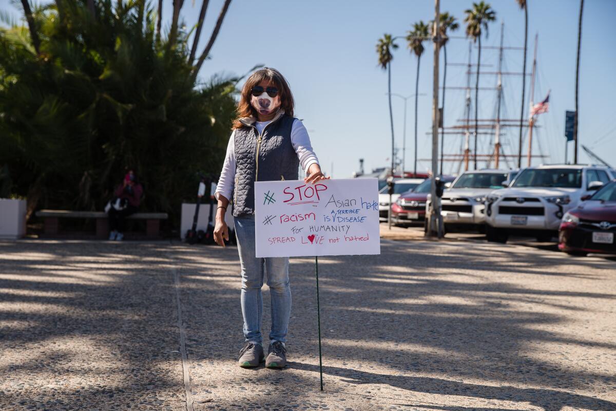 A woman with a sign "#Stop Asian hate, #racism is a terrible disease, for humanity spread love not hatred."