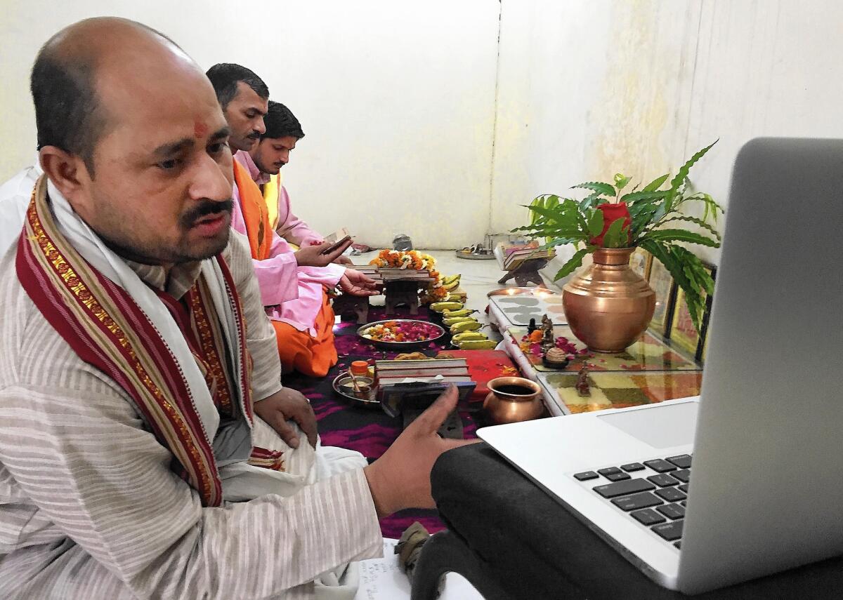 Priest Narayan Shastri, left, conducts a puja service via Skype for the Shubhpuja company in Noida, India. In Hinduism, there are elaborate pujas for virtually every life event.
