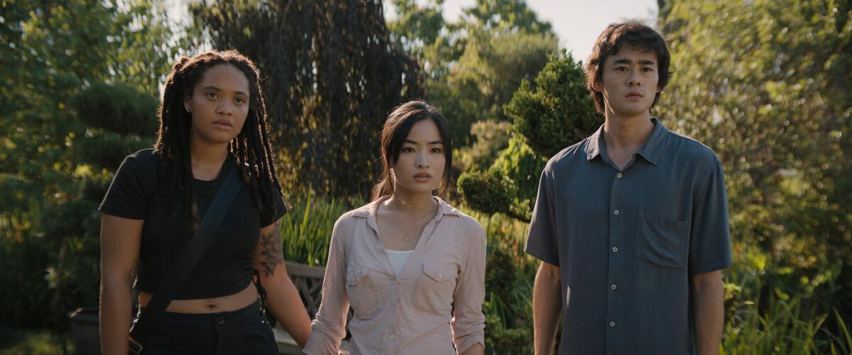 May, Cate and Kentaro stand in a wooded area surrounded by trees.