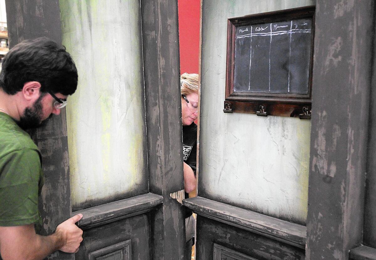 Production crew members Derek Epstein, left, and Mandy Horak carefully fit a side panel into place for one of the backdrop scenes for a recent performance of "A Christmas Carol," at South Coast Repertory on Thursday. SCR's technical and scenic crews have reassembled the same stage set for the play for over 30 years.