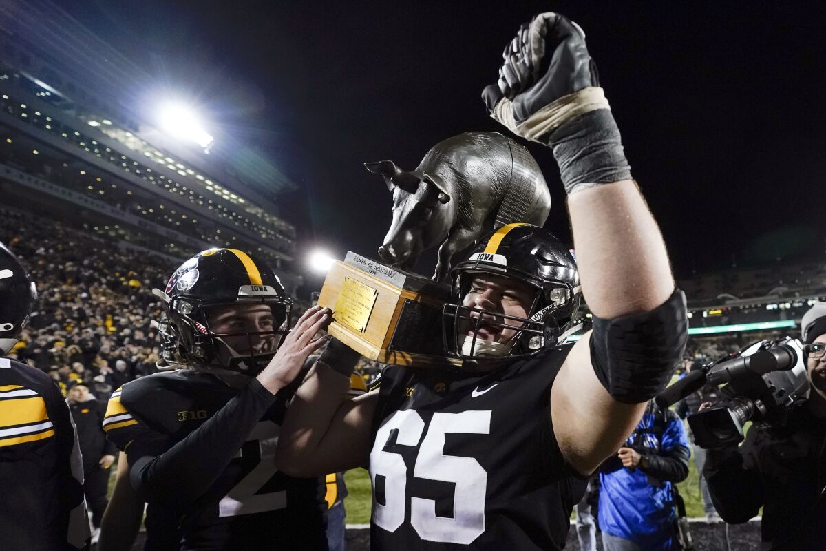 Iowa offensive lineman Tyler Linderbaum (65) carries the Floyd of Rosedale trophy off the field after an NCAA college football game against Minnesota, Saturday, Nov. 13, 2021, in Iowa City, Iowa. Iowa won 27-24. (AP Photo/Charlie Neibergall)