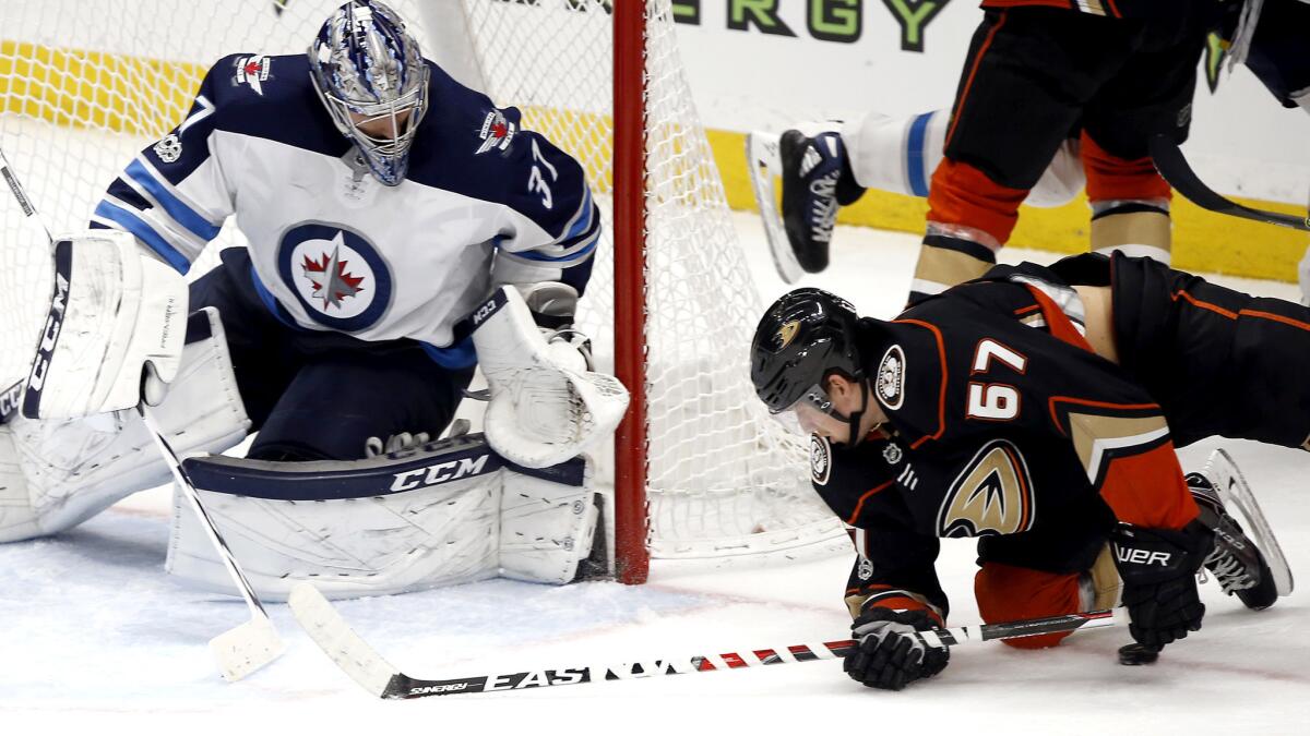 Jets goalie Connor Hellebuyck stops a shot by Ducks center Rickard Rakell during the third period Friday.