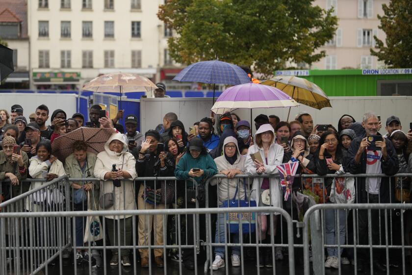Residents wait to see Britain's King Charles III and Queen Camilla Thursday, Sept. 21, 2023 in Saint-Denis, outside Paris. On the second day of his state visit to France, Charles met with sports groups in the northern suburbs of Paris and was scheduled to pay a visit to fire-damaged Notre-Dame cathedral. (AP Photo/Thibault Camus)