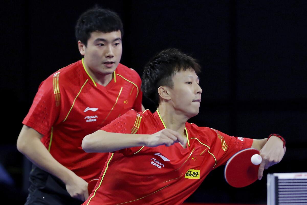 China's Liang Jingkun, left, looks on as Lin Gaoyuan, right, returns a volley during a men's doubles match on the fourth day of the 2021 World Table Tennis Championships Friday, Nov. 26, 2021, in Houston. (AP Photo/Michael Wyke)