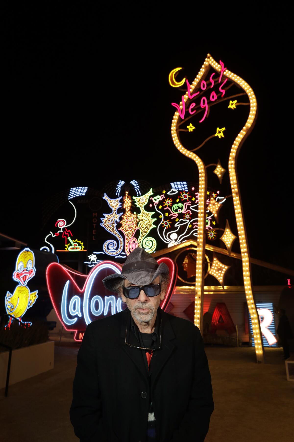 Tim Burton pauses in front of "Neon Grid Wall" and "Lost Vegas Sign Tower" at his "Lost Vegas" exhibit at the Neon Museum in Las Vegas.