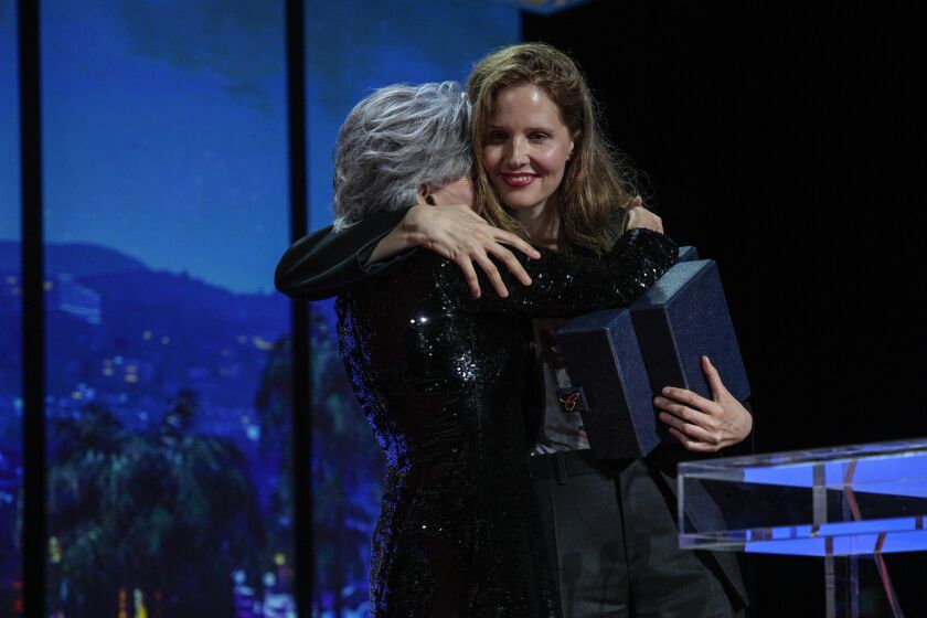 La directora de cine Justine Triet (derecha) abraza a Jane Fonda al aceptar la Palma de Oro por la cinta "Anatomie d'une chute" durante la ceremonia de premiación del 76° festival internacional de cine de Cannes, Francia, el sábado 27 de mayo de 2023. (AP Foto/Daniel Cole)