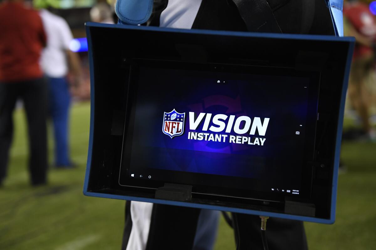 Instant replay equipment is carried on the sidelines before an NFL game.