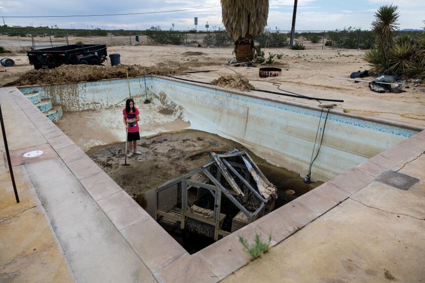 TWENTYNINE PALMS, CA - AUGUST 1, 2024: Colin McGorty-Weir, 15, has been helping his family clear out their backyard pool which is still full of mud and a "catio," which got washed off the house during the July 14 monsoonal storm on August 1, 2024 in Twentynine Palms, California. Many residents who were hit with severe flooding don't live in a flood zone so they don't have flood insurance and are facing the prospect of recovering without and help from their insurance companies and little government support.(Gina Ferazzi / Los Angeles Times)