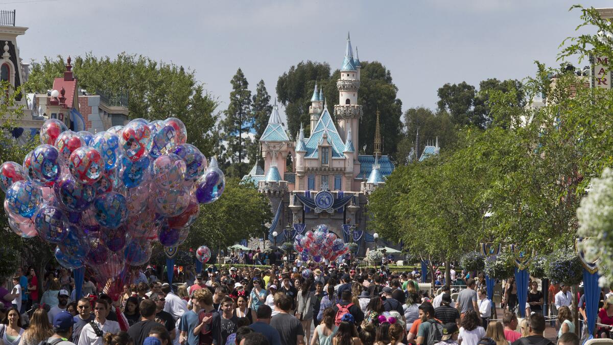 A large crowd strolls down Main Street, U.S.A., at Disneyland.