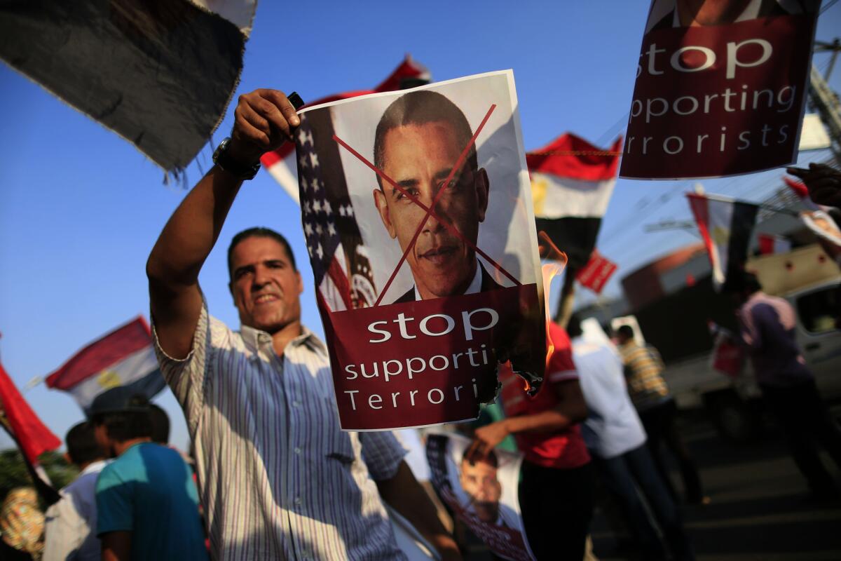 An opponent of ousted Egyptian President Mohamed Morsi burns a poster of President Obama at a rally in Cairo, Egypt.