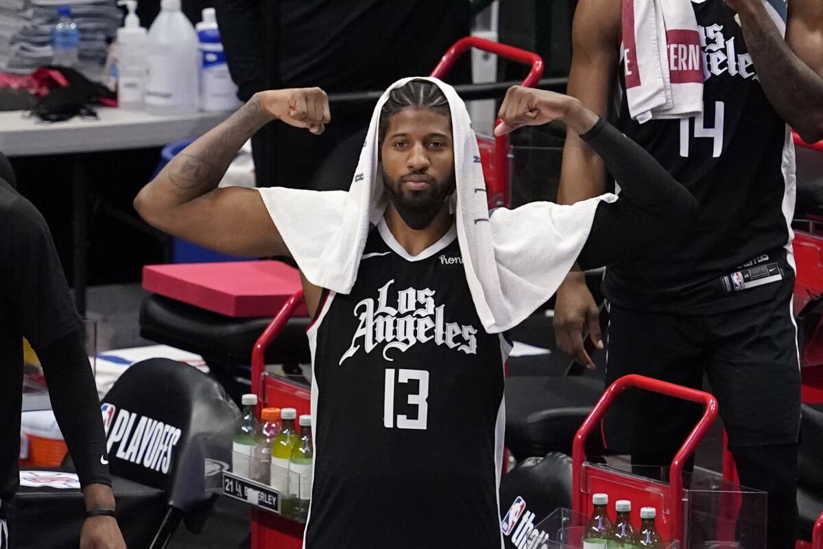 Los Angeles Clippers' Paul George stands by the bench celebrating a basket