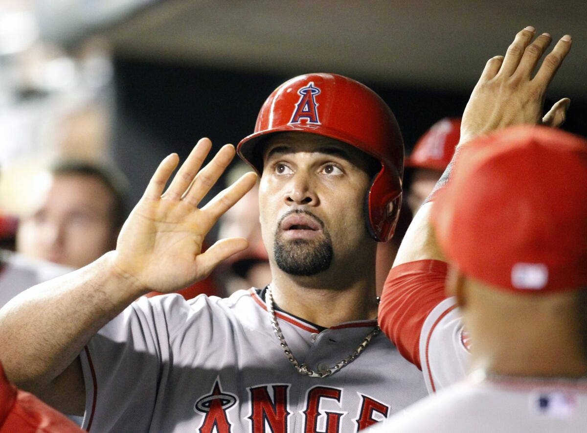 Albert Pujols is congratulated by Angels teammates after scoring on a single by Howie Kendrick off Minnesota pitcher Anthony Swarzak during the ninth inning Saturday night in Minneapolis.