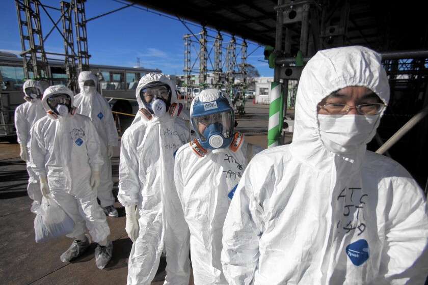 Workers in protective suits and masks wait to enter the emergency operation center at the crippled Fukushima Dai-ichi nuclear power station in Okuma, Japan, on Nov. 12, 2011.