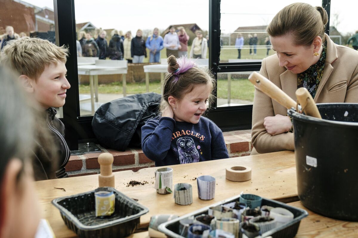 Danish Prime Minister Mette Frederiksen, right, meets Ukrainian refugee children at Paradisbakken school in Nexoe, as she visits the island of Bornholm in Denmark, Thursday, April 7, 2022. Anna Prokopiuk, center, is from Ukraine but has lived in Denmark for three years and is therefore able to help interpret for the newly arrived refugees. (Pelle Rink/Ritzau Scanpix via AP)