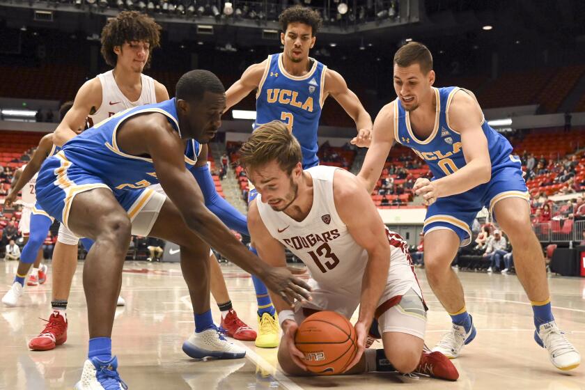 Washington State forward Jeff Pollard (13) gets on the floor to grab a loose ball as UCLA guard Prince Ali, left, guard Jules Bernard, center, and forward Alex Olesinski (0) look to tie him up before Pollard called a time out in the first half of an NCAA college basketball game, Saturday, Jan. 4, 2020, in Pullman, Wash. (Pete Caster/Lewiston Tribune via AP)
