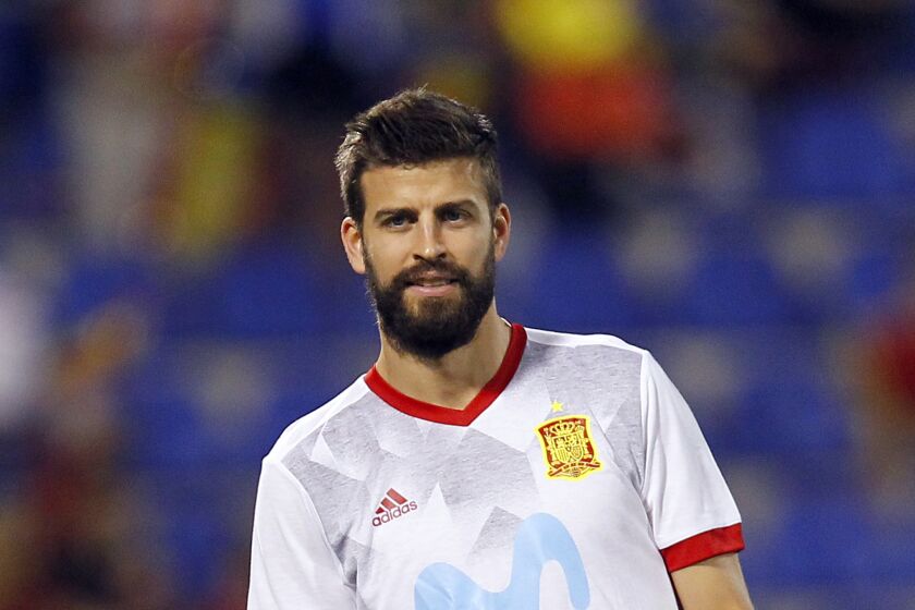 A man with brown hair and facial hair in a soccer jersey