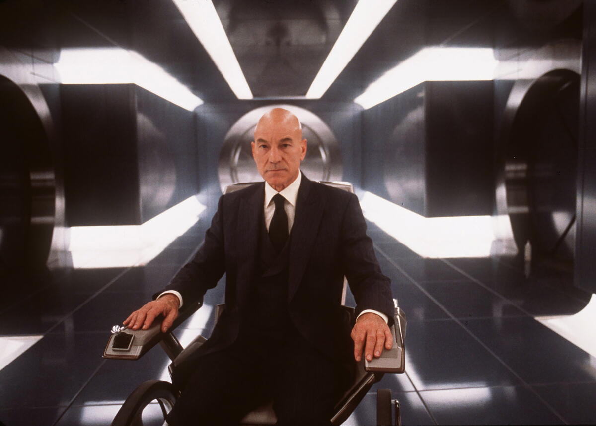 A man in a dark suit and tie, seated in a wheelchair