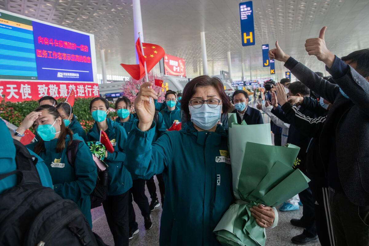 Medical staff members (in green) from Peking Union Medical College Hospital wave national flags before leaving Tianhe airport in Wuhan, China.