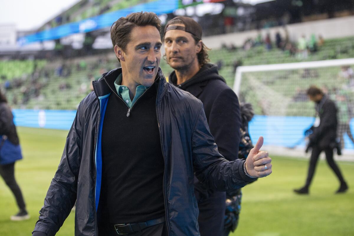 Austin FC coach Josh Wolff, left, and actor Matthew McConaughey walk on the field before a match in February. 
