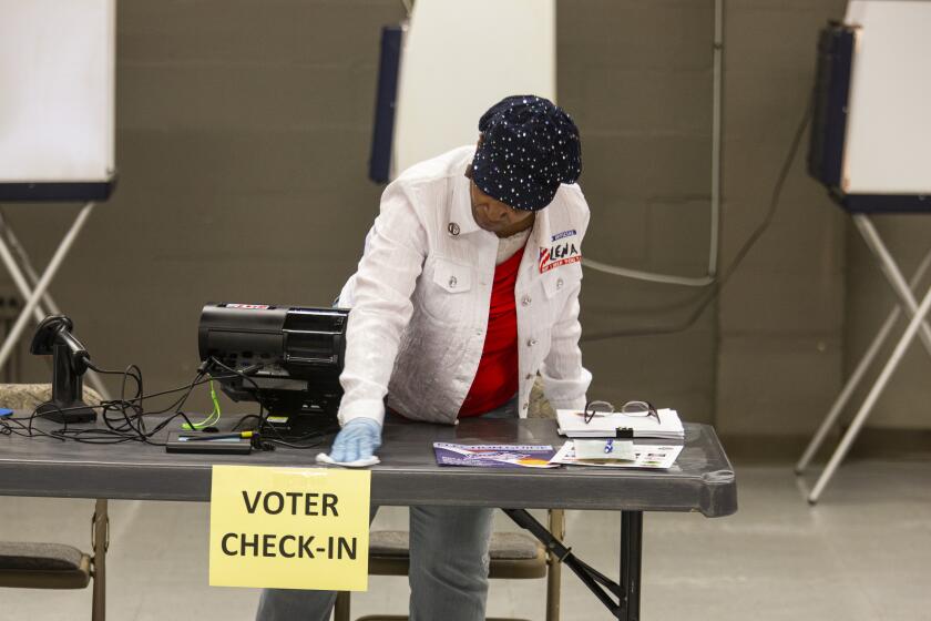 Leon County, Florida poll worker Lena Simmonds wipes up a voter check-in counter while waiting on voters to arrive on March 17, 2020 in Tallahassee, Florida.