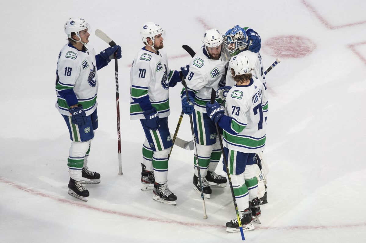 Vancouver Canucks' Jake Virtanen (18), Tanner Pearson (70), J.T. Miller (9), goalie Thatcher Demko (35) and Tyler Toffoli (73) celebrate the team's win over the Vegas Golden Knights in Game 5 of an NHL hockey second-round playoff series, Tuesday, Sept. 1, 2020, in Edmonton, Ontario. (Jason Franson/The Canadian Press via AP)