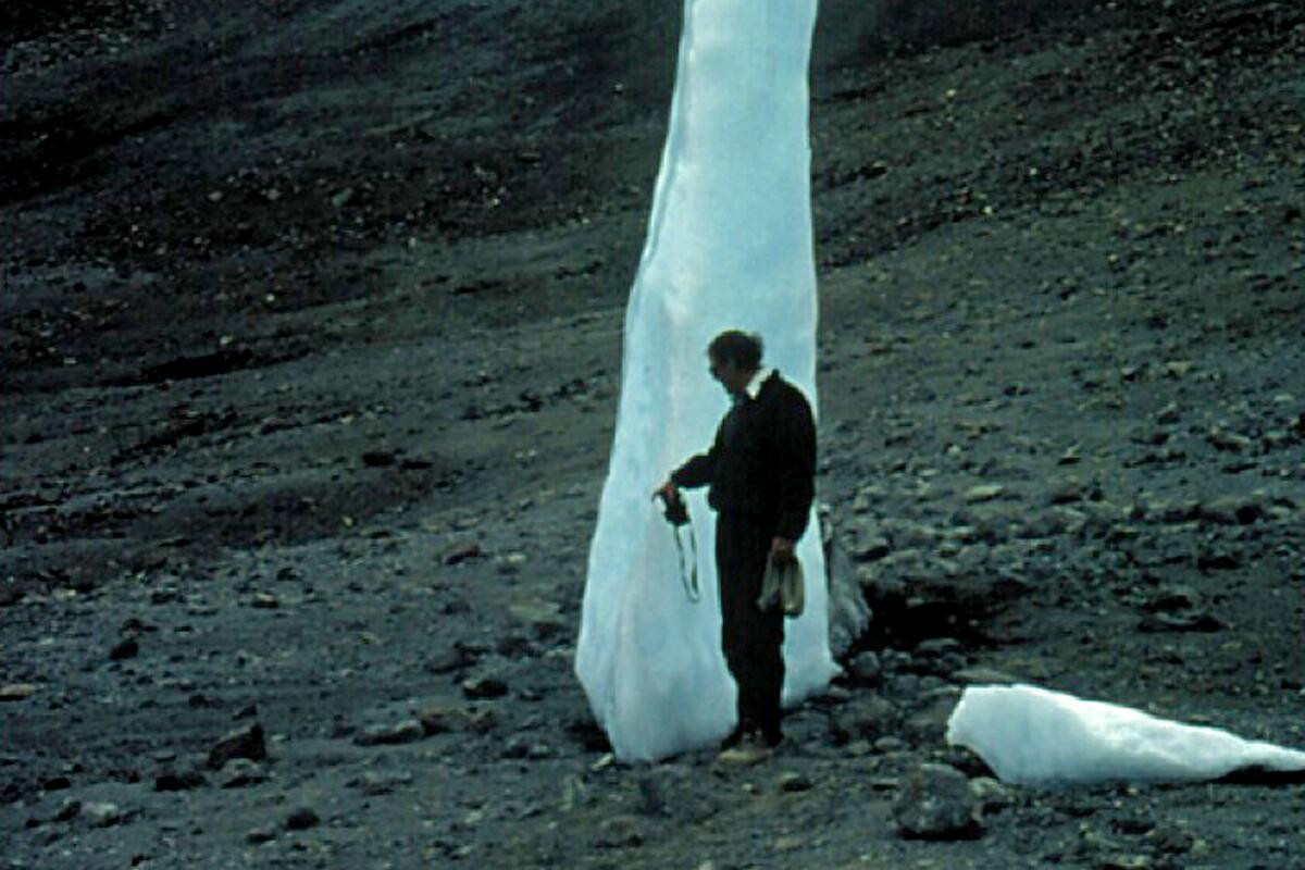 A man stands at a melting glacier.