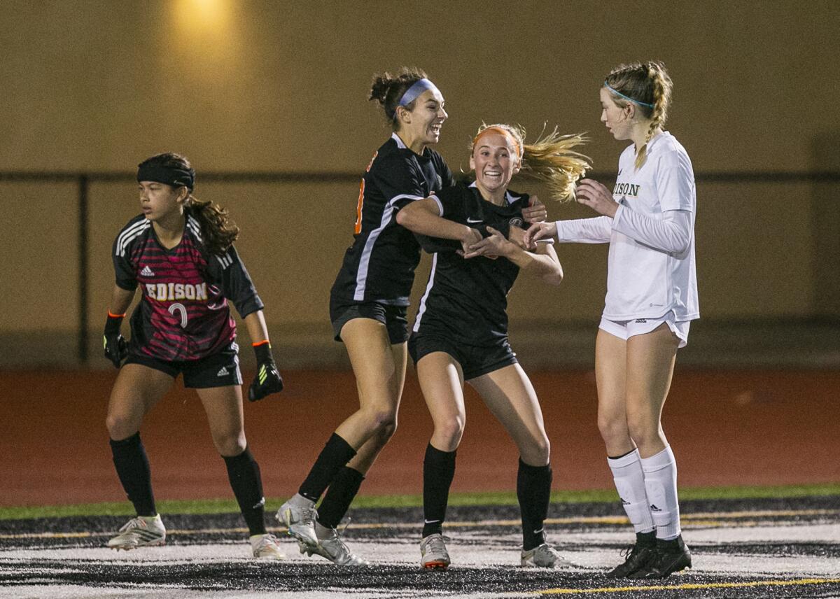 Huntington Beach's Solana Van Enoo, center, hugs Sienna McAthy after she scored the game-winning goal against Edison.