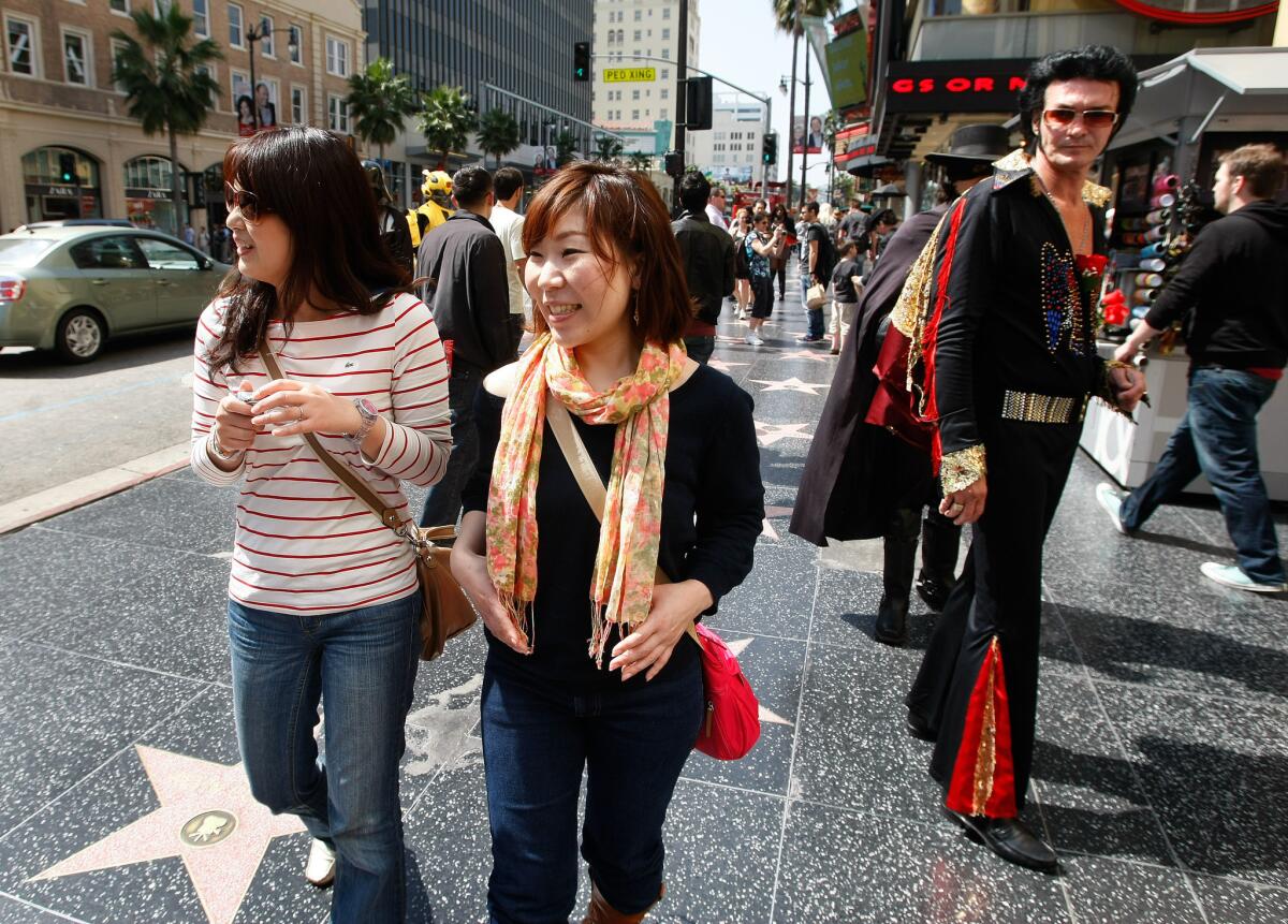 Tourists Miwako Tsugawa, left, and Yuka Watanabe, from Nagoya, Japan, check out the sights while walking along Hollywood Boulevard.