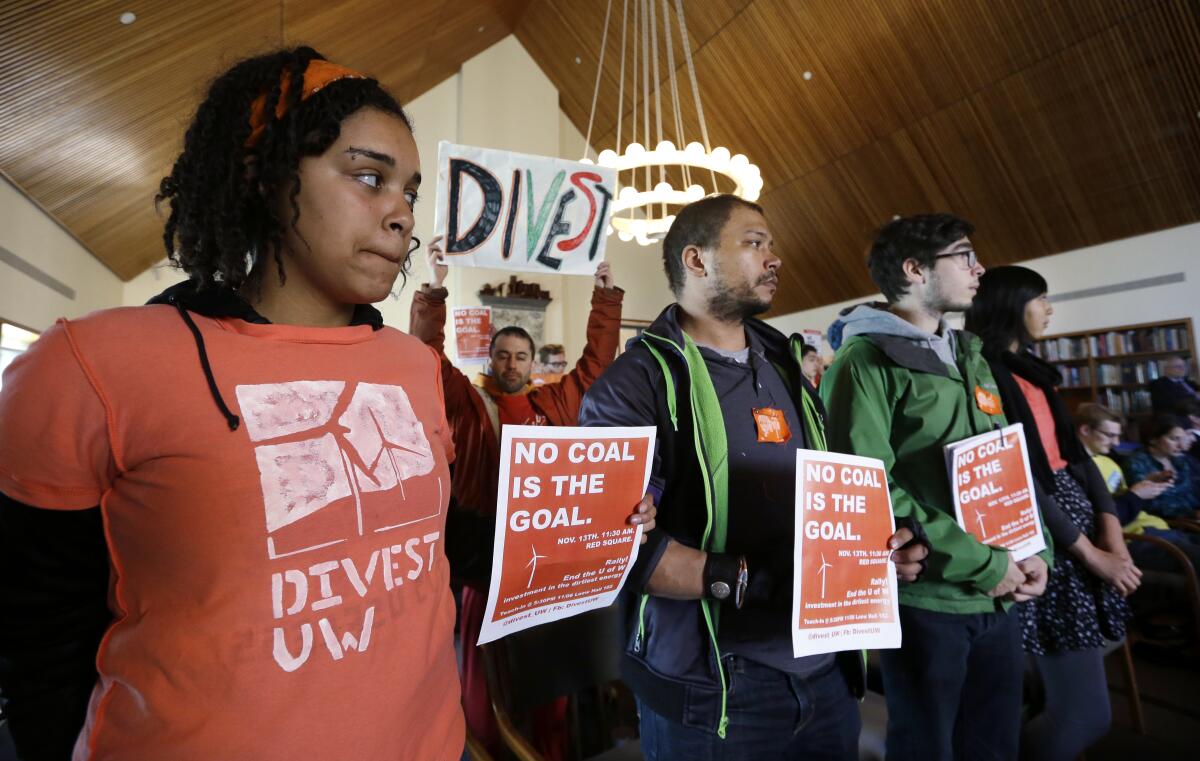 Protesters hold divestment signs at a meeting