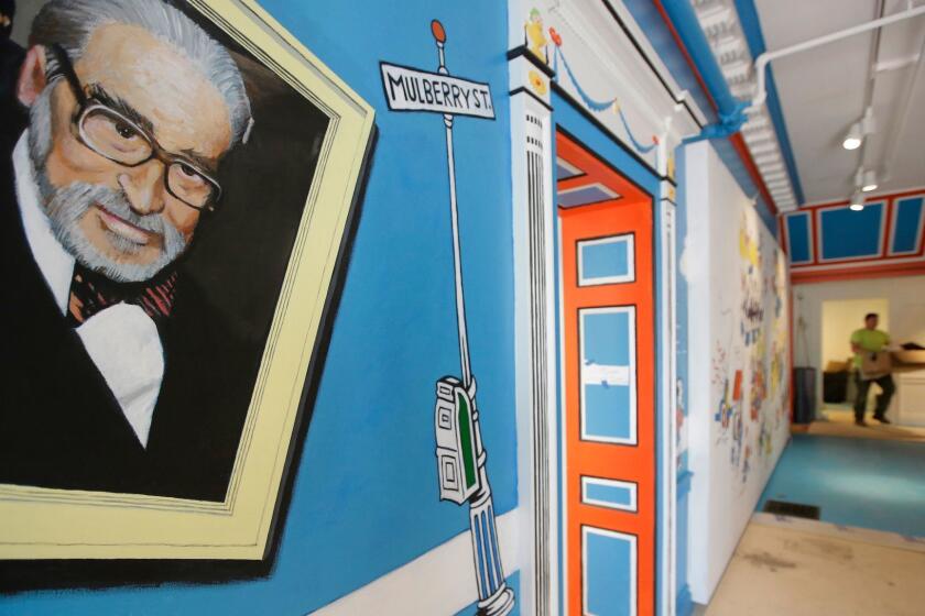 In this May 4, 2017, photo a mural that features Theodor Seuss Geisel, left, also know by his pen name Dr. Seuss, rests on a wall near an entrance at The Amazing World of Dr. Seuss Museum, in Springfield, Mass. The new museum devoted to Dr. Seuss opened on June 3 in his hometown. (AP Photo/Steven Senne)