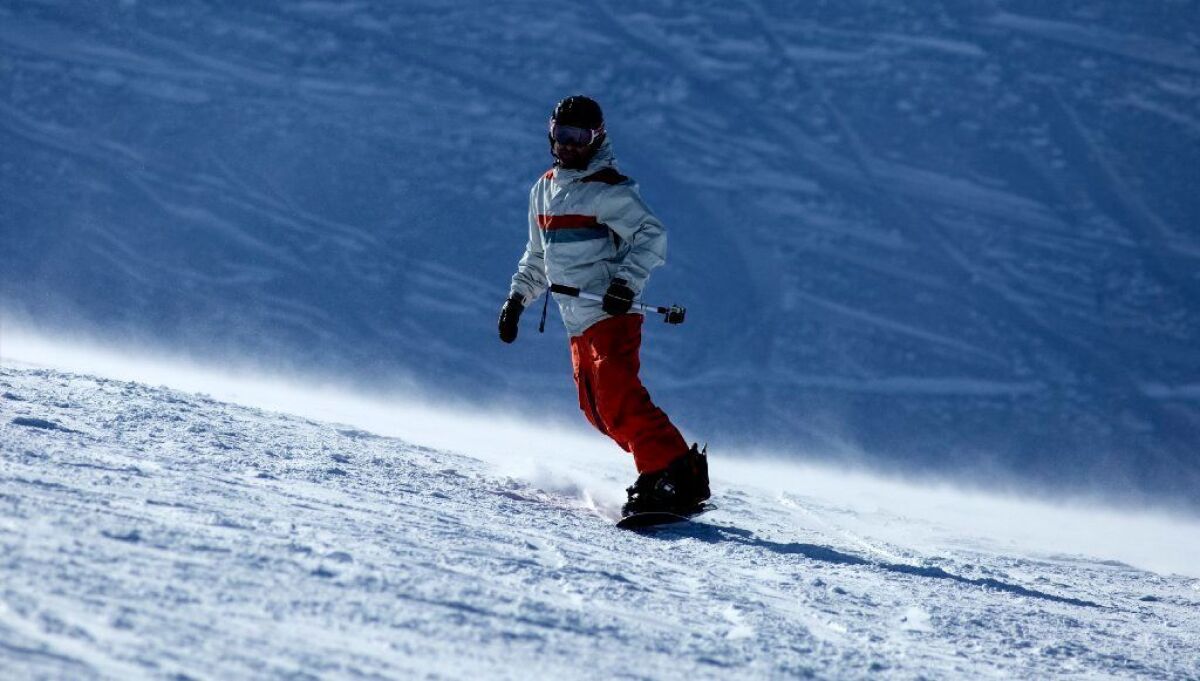 A snowboarder carves down a run at Mammoth Mountain. The deal under which a Colorado partnership acquired Mammoth Resorts was completed Monday.
