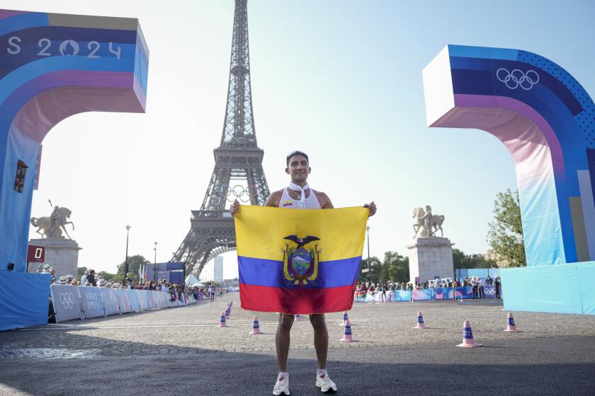 El ecuatoriano Brian Daniel Pintado posa con la bandera de su país frente a la torre Eiffel tras cruzar primero la meta de la prueba de 20km de marcha atlética, en los Juegos de París, el 1 de agosto de 2024. (AP Foto/Vadim Ghirda)