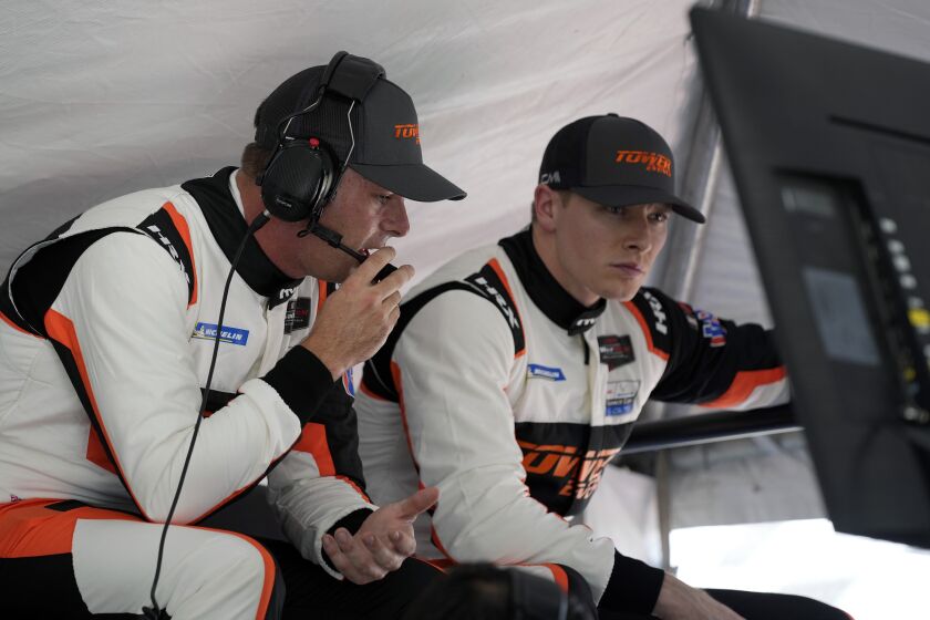 Scott McLaughlin, left, of New Zealand and Josef Newgarden look over a monitor in their pit stall during auto race testing for the upcoming Rolex 24 hour race at Daytona International Speedway, Friday, Jan. 20, 2023, in Daytona Beach, Fla. (AP Photo/John Raoux)