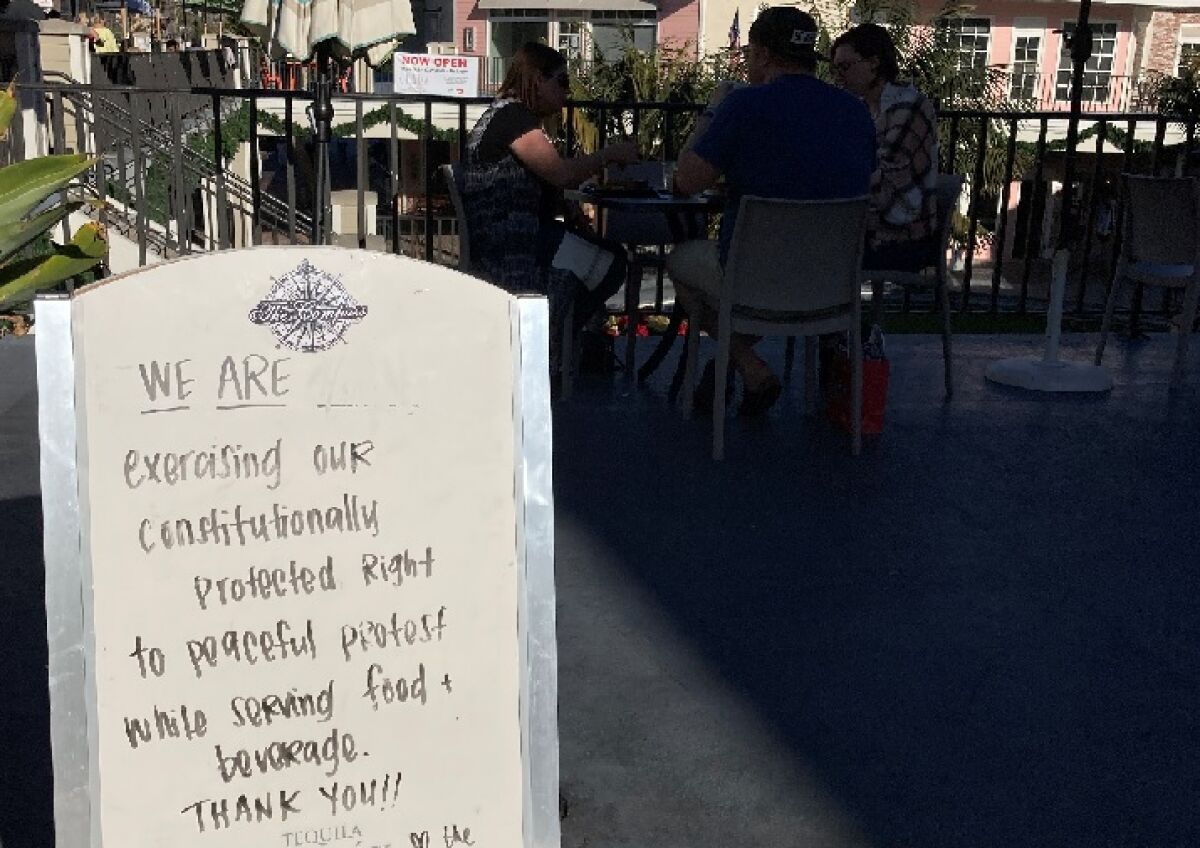 A sign outside The Compass says the restaurant is open as a "peaceful protest" of county orders.