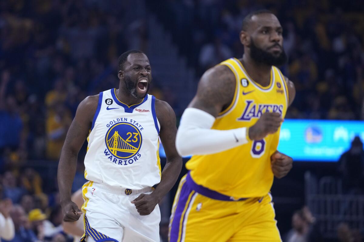 Warriors forward Draymond Green lets out a yell after making a three-pointer with Lakers forward LeBron James nearby.