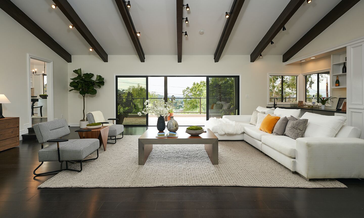 The living room is spacious with dark wood ceiling beams and sliding glass doors to the back.