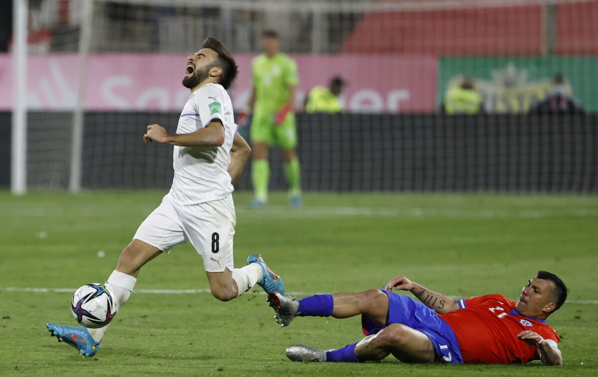 Uruguay's Diego Rossi, left, is fouled by Chile's Gary Medel during a qualifying soccer match for the FIFA World Cup Qatar 2022 at San Carlos de Apoquindo stadium in Santiago, Chile, Tuesday, March 29, 2022. (Alberto Valdes/Pool Via AP)
