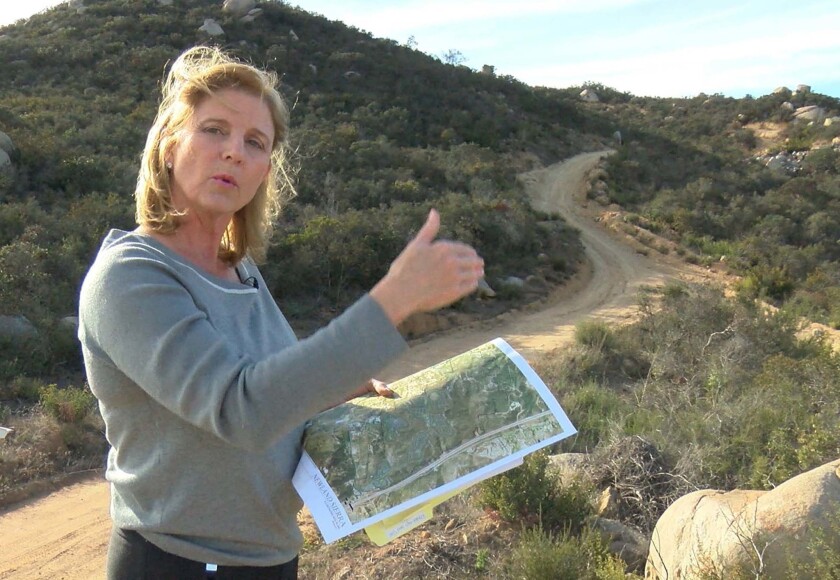 Rita Brandin, Sr. VP ad Development Director for Newland Sierra, with a map near the high point of the property. The 1,800 acres of the proposed Newland Sierra development project is in the Twin Oaks area north of Escondido. 2,135 residential units are planned and a small commercial development.