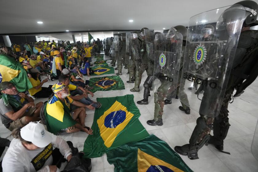 Protesters, supporters of Brazil's former President Jair Bolsonaro, are confronted by police in riot gear after they stormed the Planalto Palace in Brasilia, Brazil, Sunday, Jan. 8, 2023. Planalto is the official workplace of the president of Brazil. (AP Photo/Eraldo Peres)