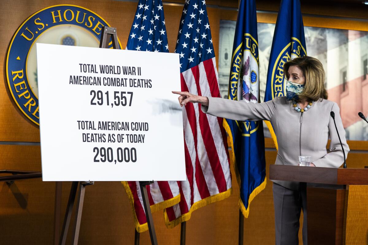 House Speaker Nancy Pelosi points at a poster illustrating the number American deaths because of COVID-19. 