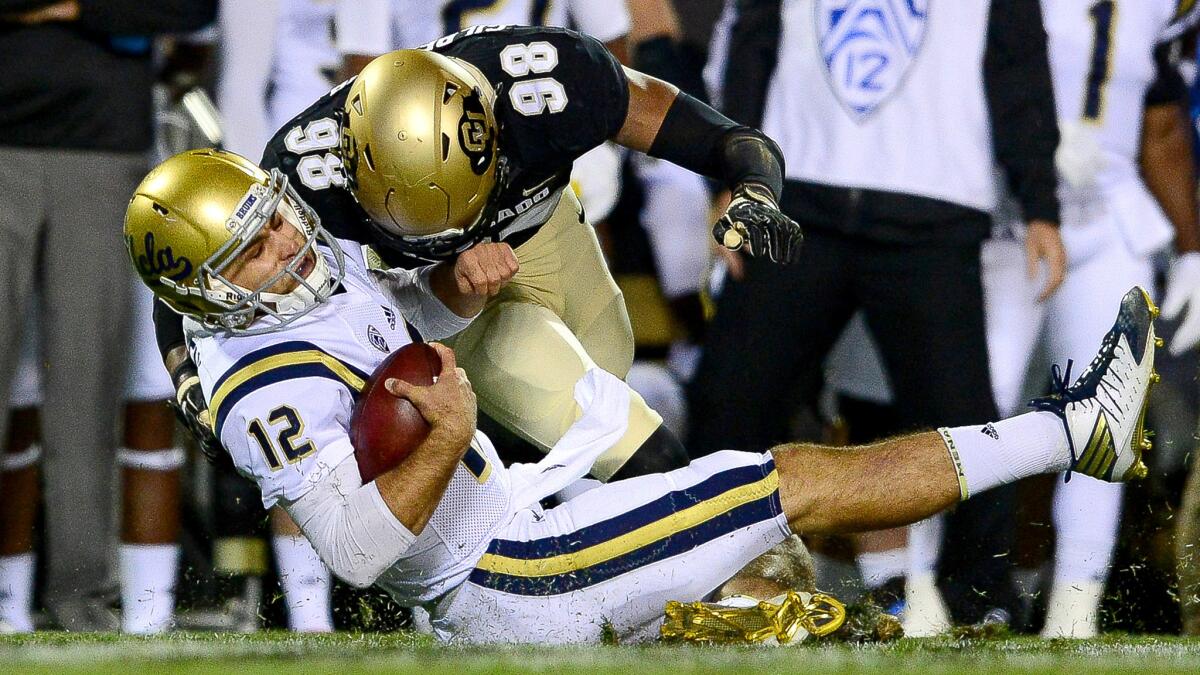 UCLA quarterback Mike Fafaul is brought down by Colorado linebacker Jimmie Gilbert during a play in the first quarter that resulted in a targeting penalty and ejection.
