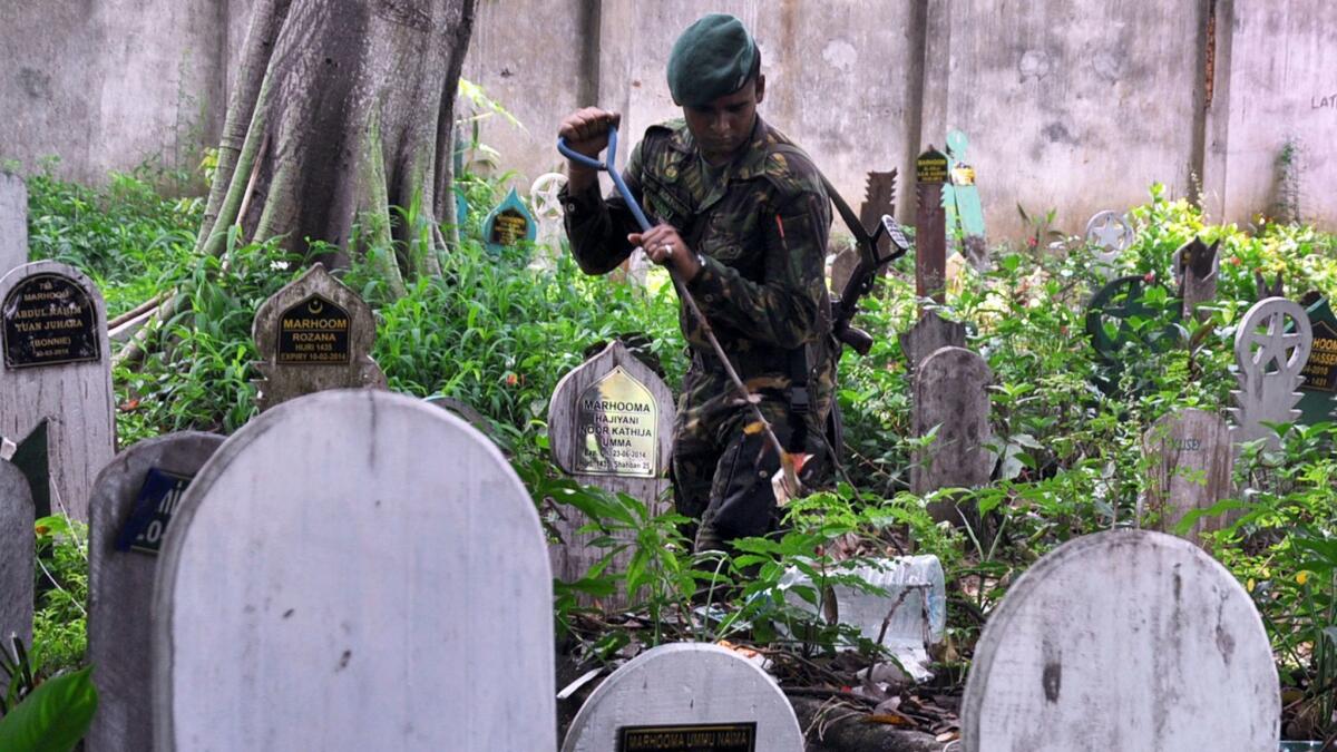 A Sri Lankan police special task force officer inspects a Muslim cemetery in Colombo on April 29.