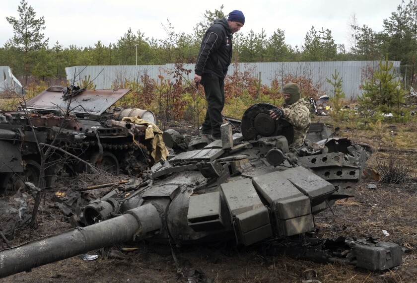 A Ukrainian soldier examines a destroyed Russian tank