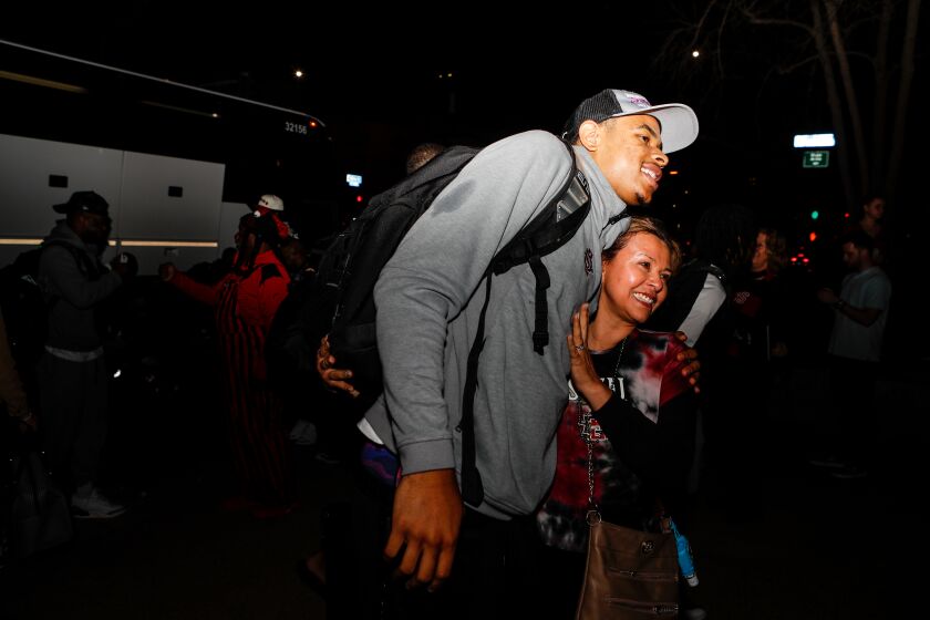 San Diego, CA - March 18: San Diego State's Keshad Johnson hugs a fan after the Aztecs' arrived back on campus outside the Fowler Athletic Center on Saturday, March 18, 2023 in San Diego, CA. The Aztecs defeated No. 12-seeded College of Charleston (63-57) and No. 13 seeded Furman (75-52) to advance to next week's Sweet 16 in Louisville, Kentucky. (Meg McLaughlin / The San Diego Union-Tribune)